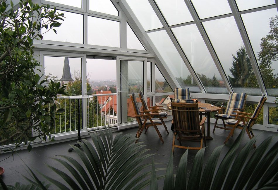 Blick aus einem Wintergarten mit Holzmöbeln heraus