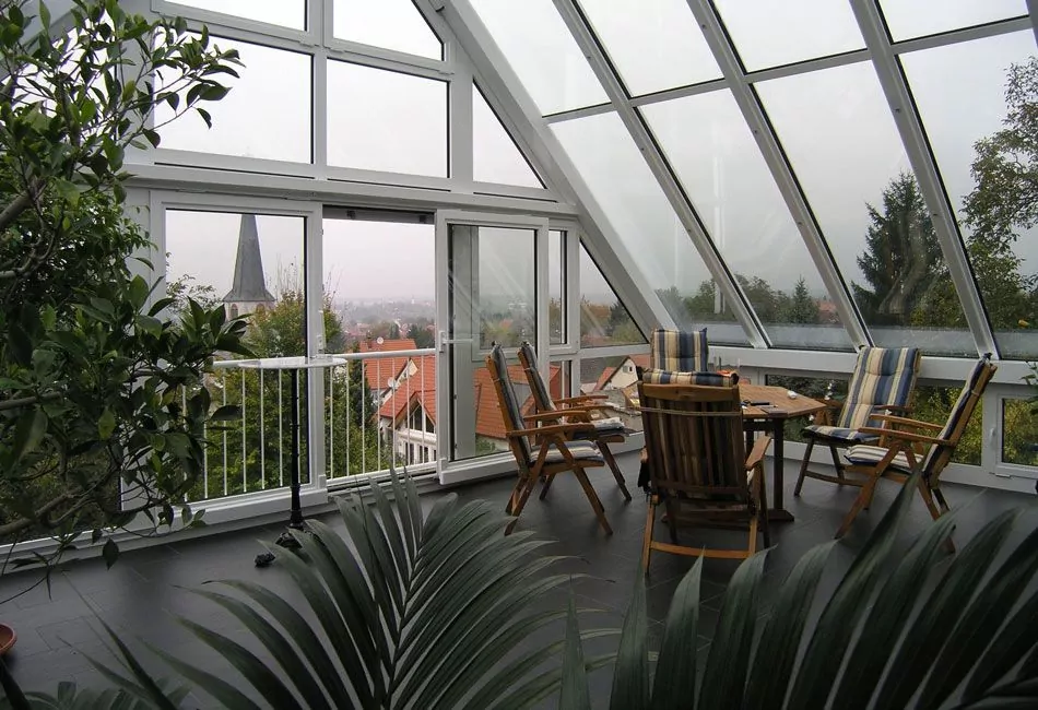Blick aus einem Wintergarten mit Holzmöbeln heraus